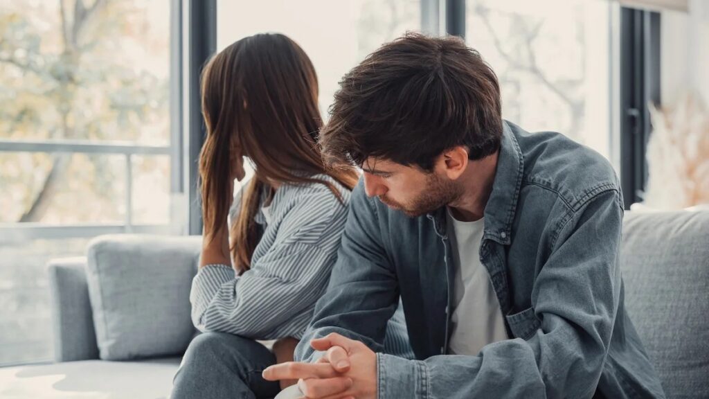 Femme pensive pendant que son mari lui adresse des reproches lors d'une dispute de couple